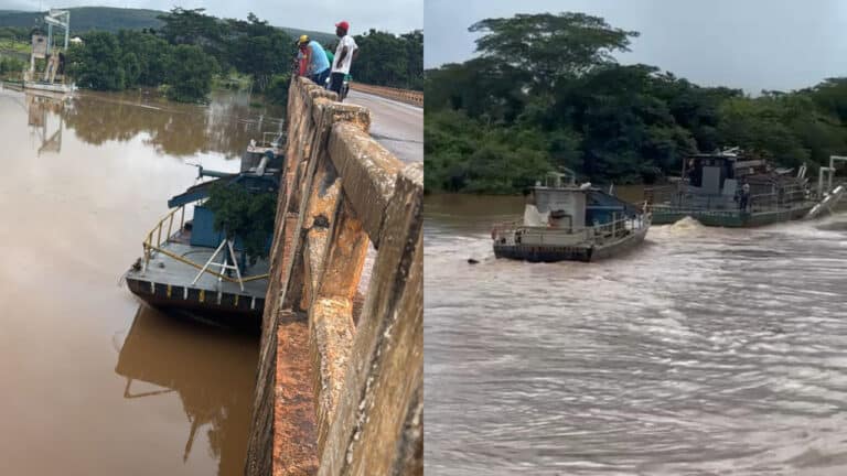 Barco retira balsa de dragagem presa sob a ponte do Rio Paracatu em Brasilândia de Minas durante cheia